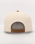 Beige cap with brown leather accents on a light gray background