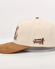 Beige and brown cap with embroidered design on a white background