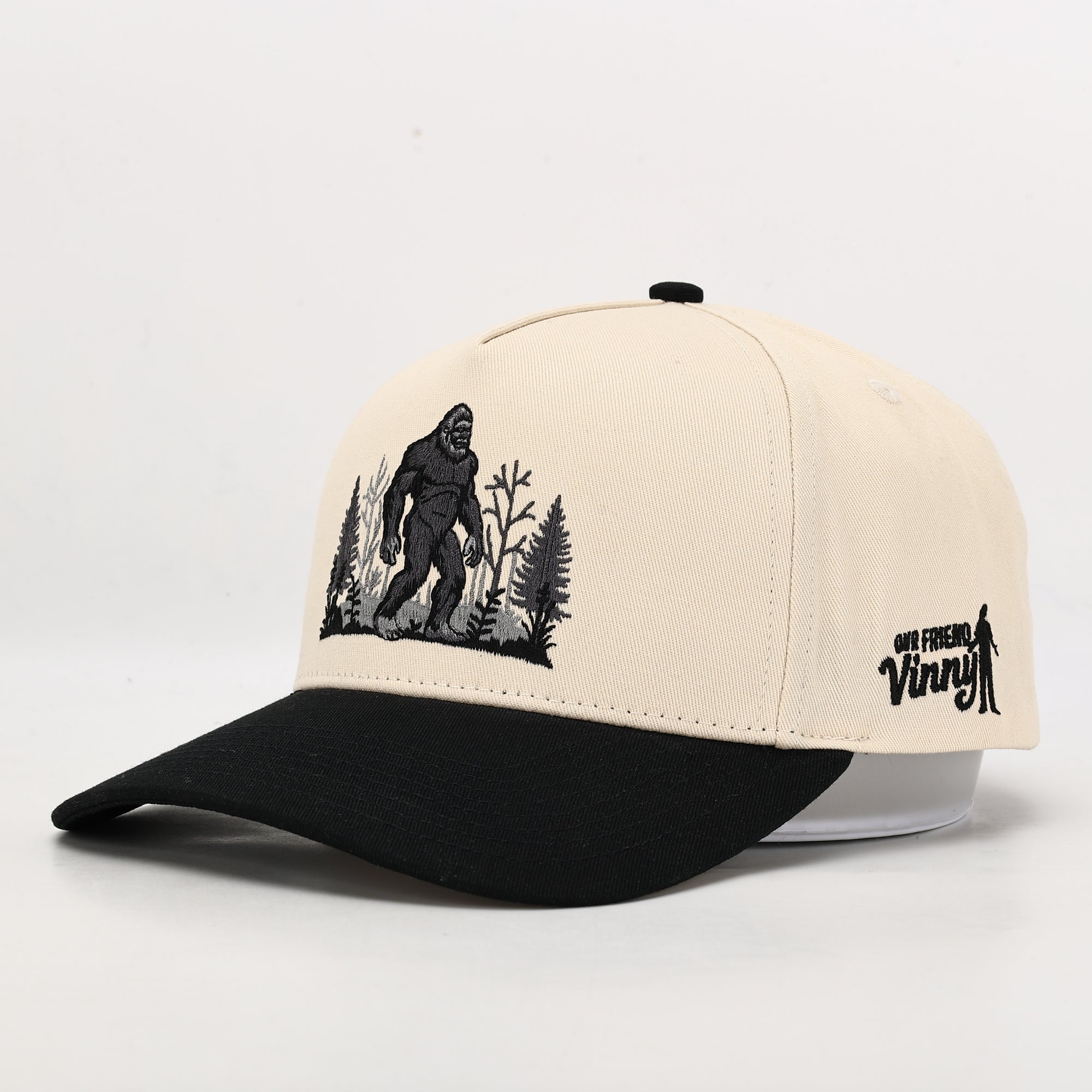 Beige and black cap with a Sasquatch graphic on a white background