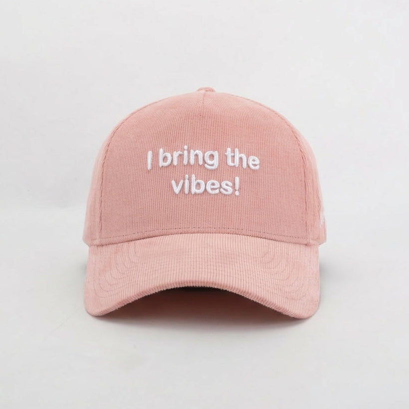 Pink cap with 'I bring the vibes!' text on a light gray background