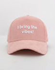 Pink cap with 'I bring the vibes!' text on a light gray background