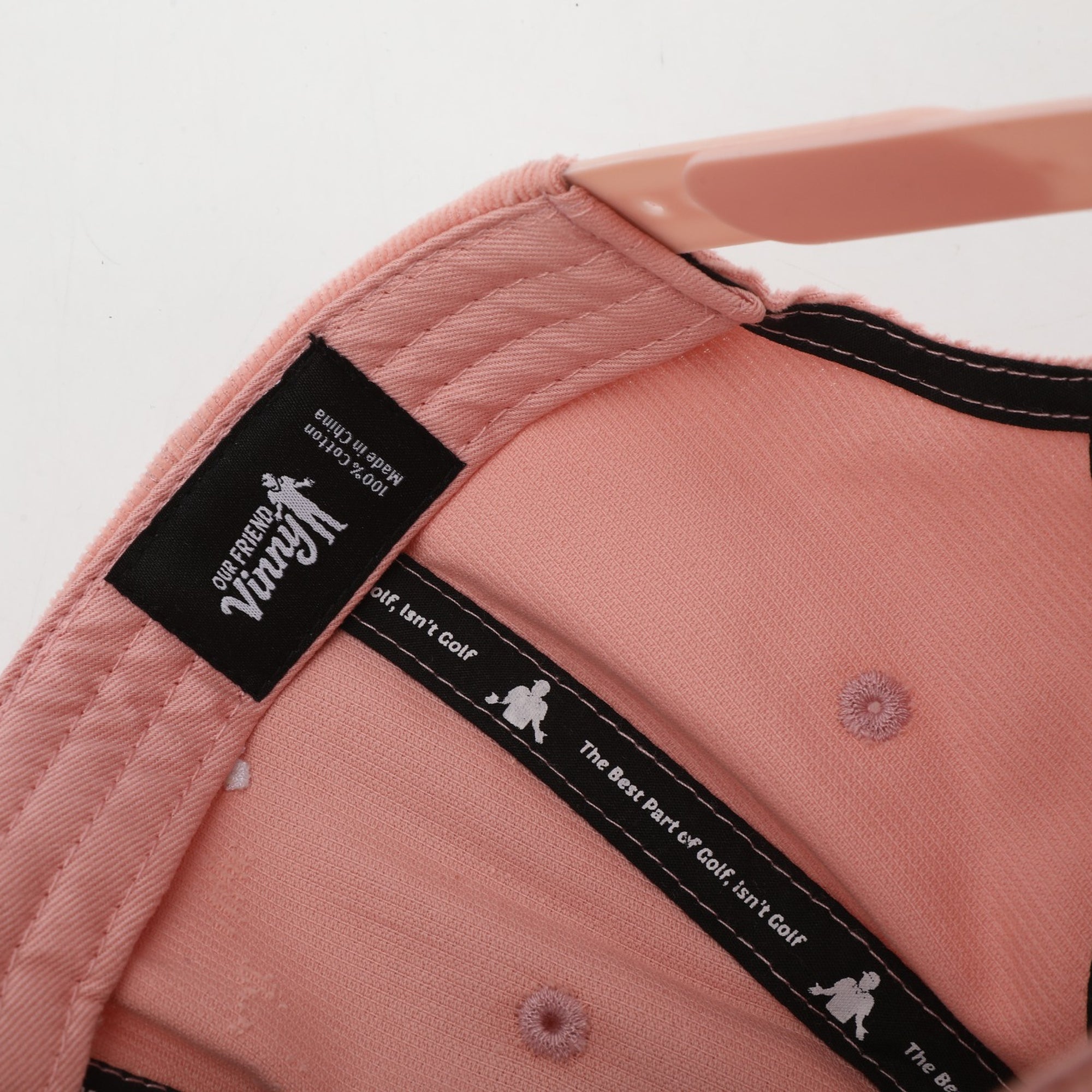 Close-up of a pink cap with a brand label on a white background