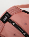 Close-up of a pink cap with a brand label on a white background
