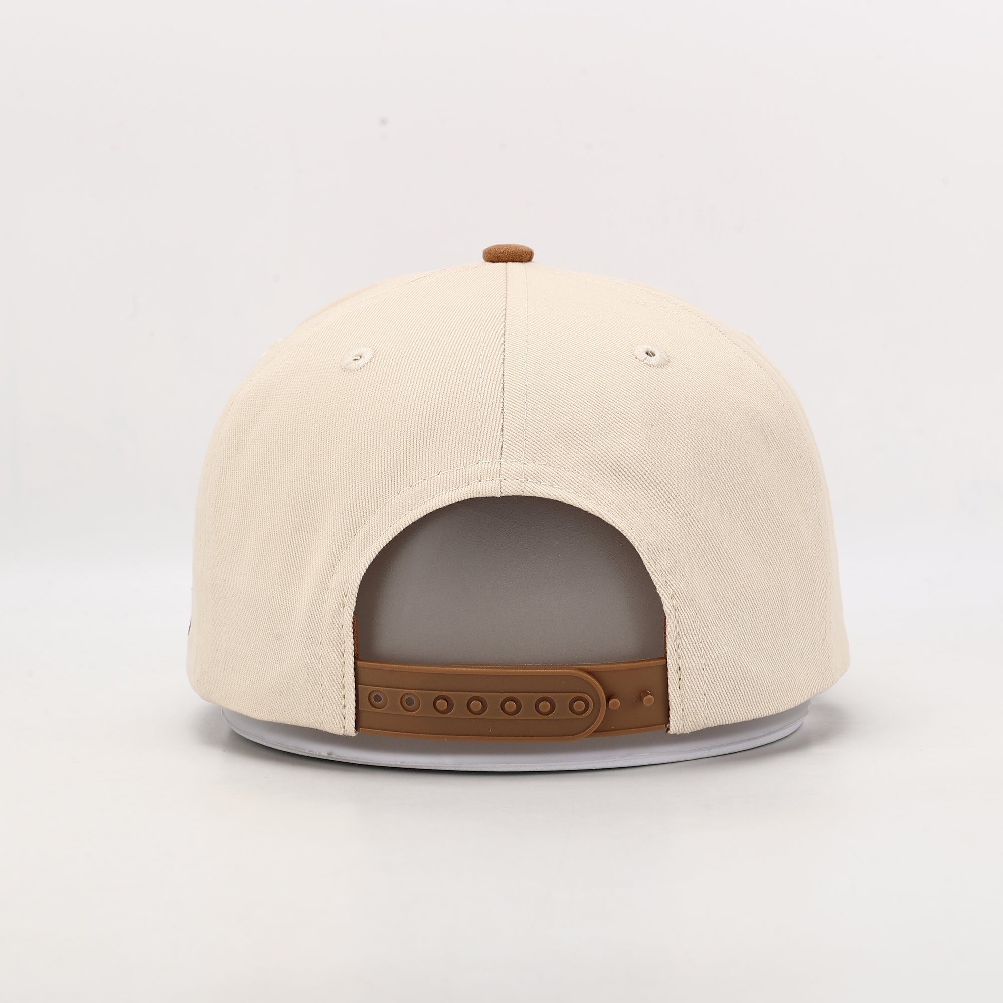 Beige cap with brown leather accents on a light gray background