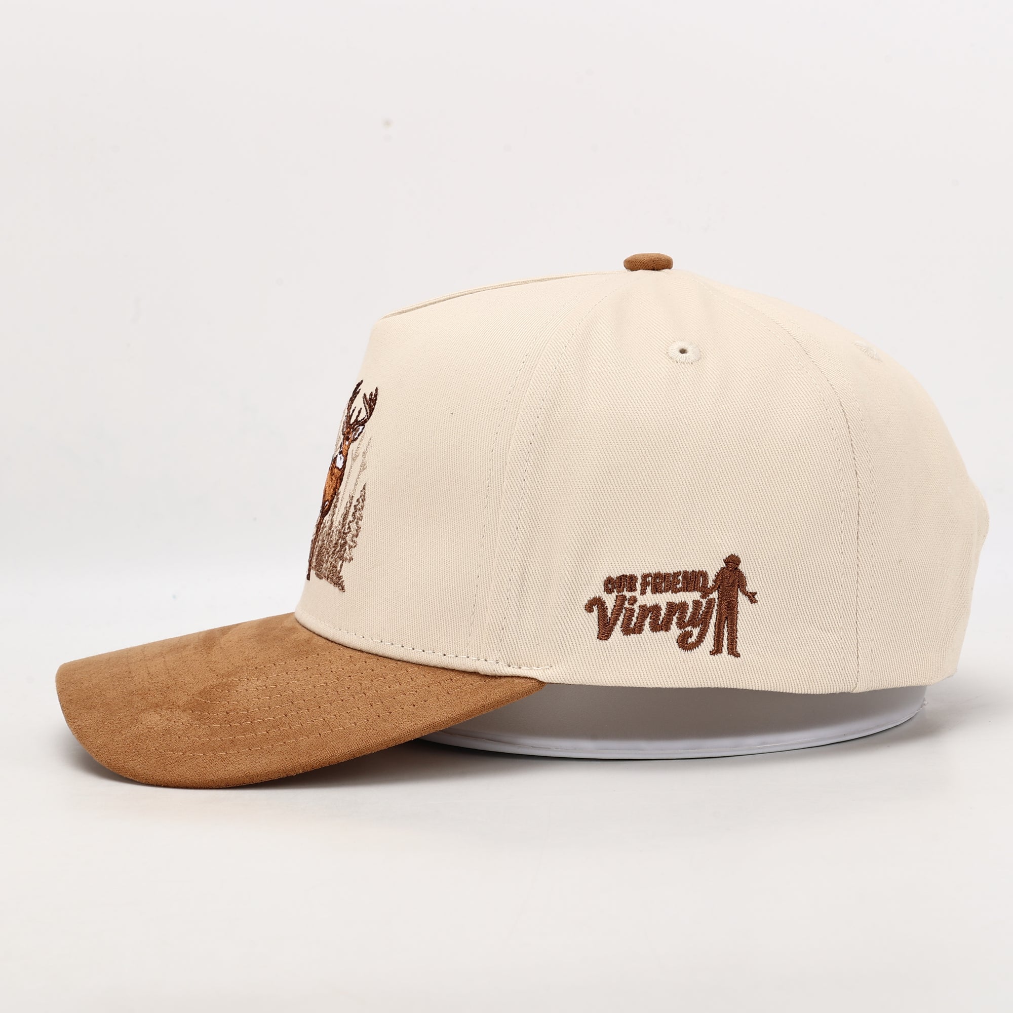 Beige and brown cap with embroidered design on a white background