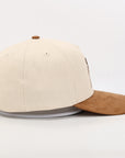 Beige and brown baseball cap on a light gray background