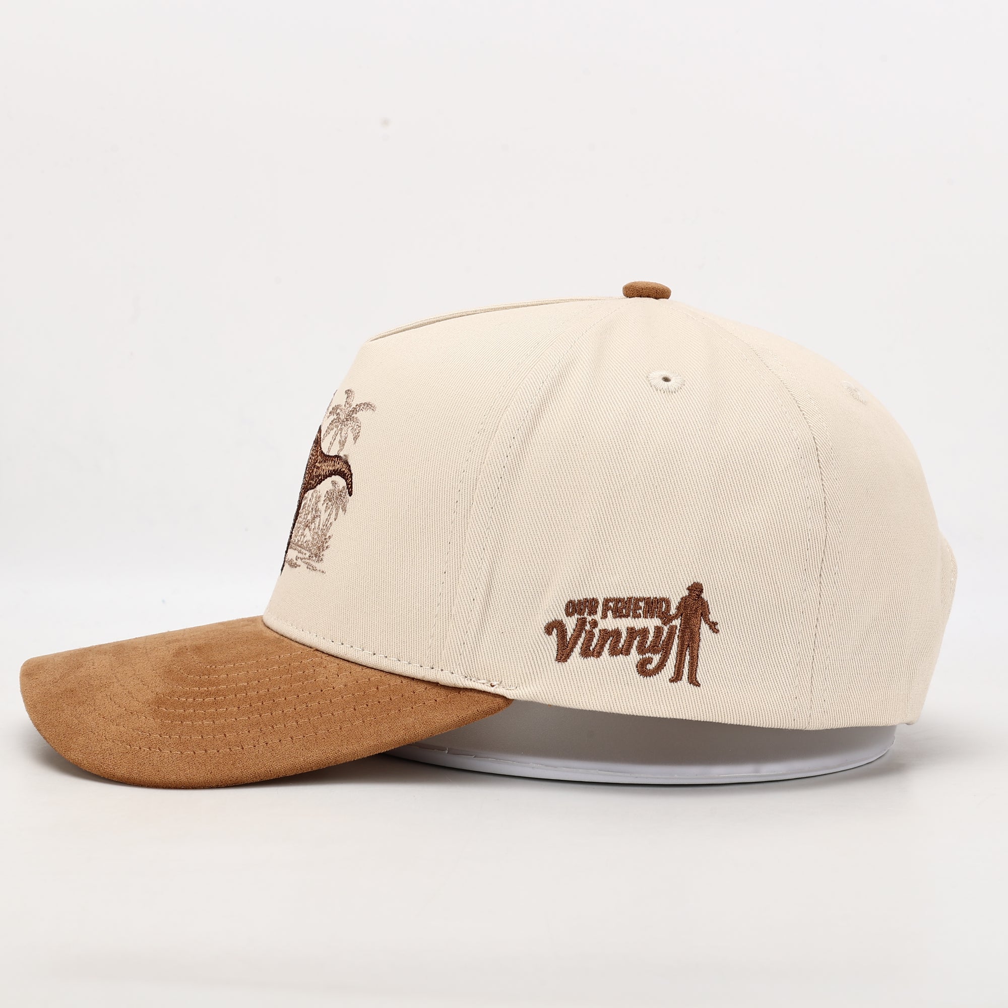 Beige and brown cap with embroidered design on a white background