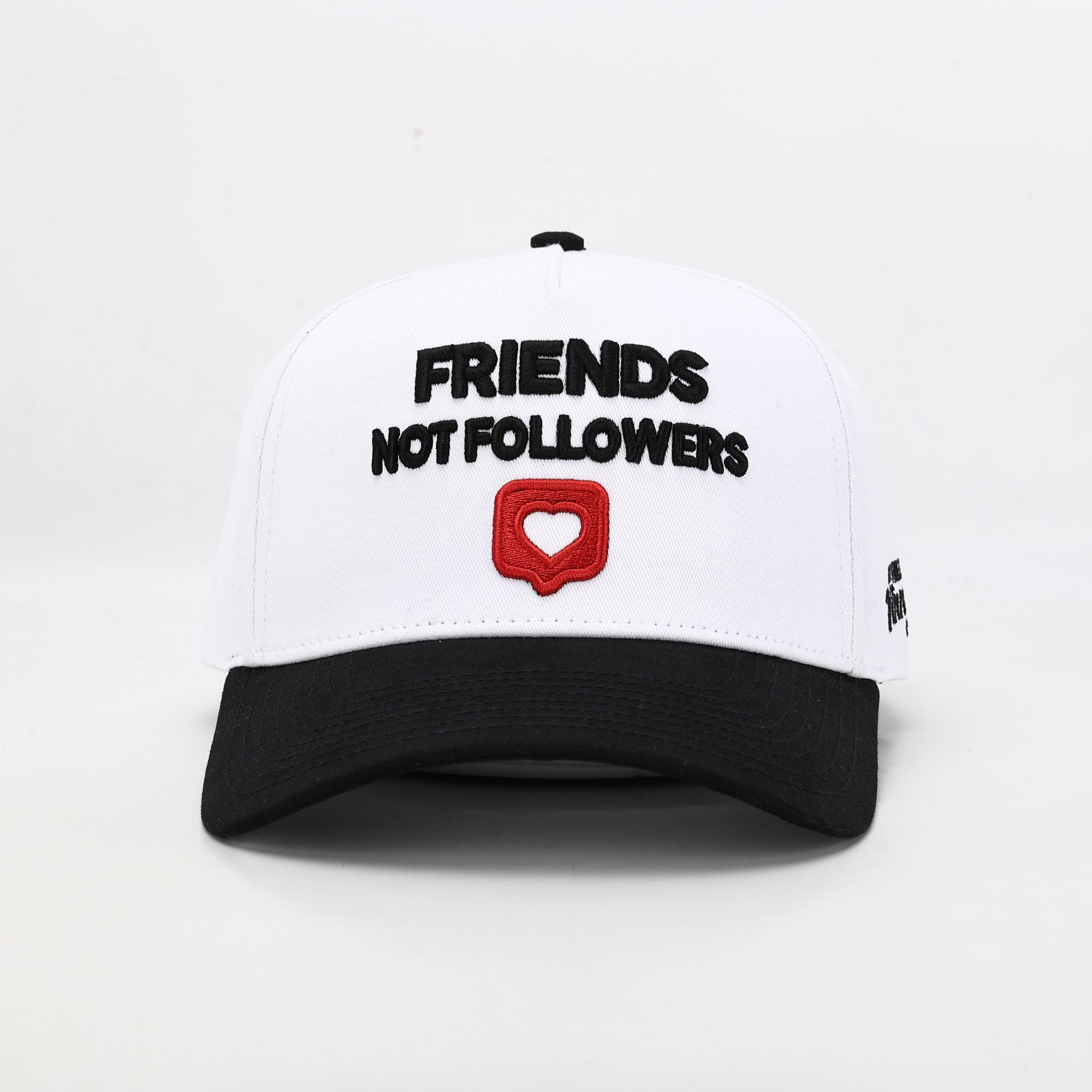 White cap with black text 'FRIENDS NOT FOLLOWERS' and a red heart symbol 