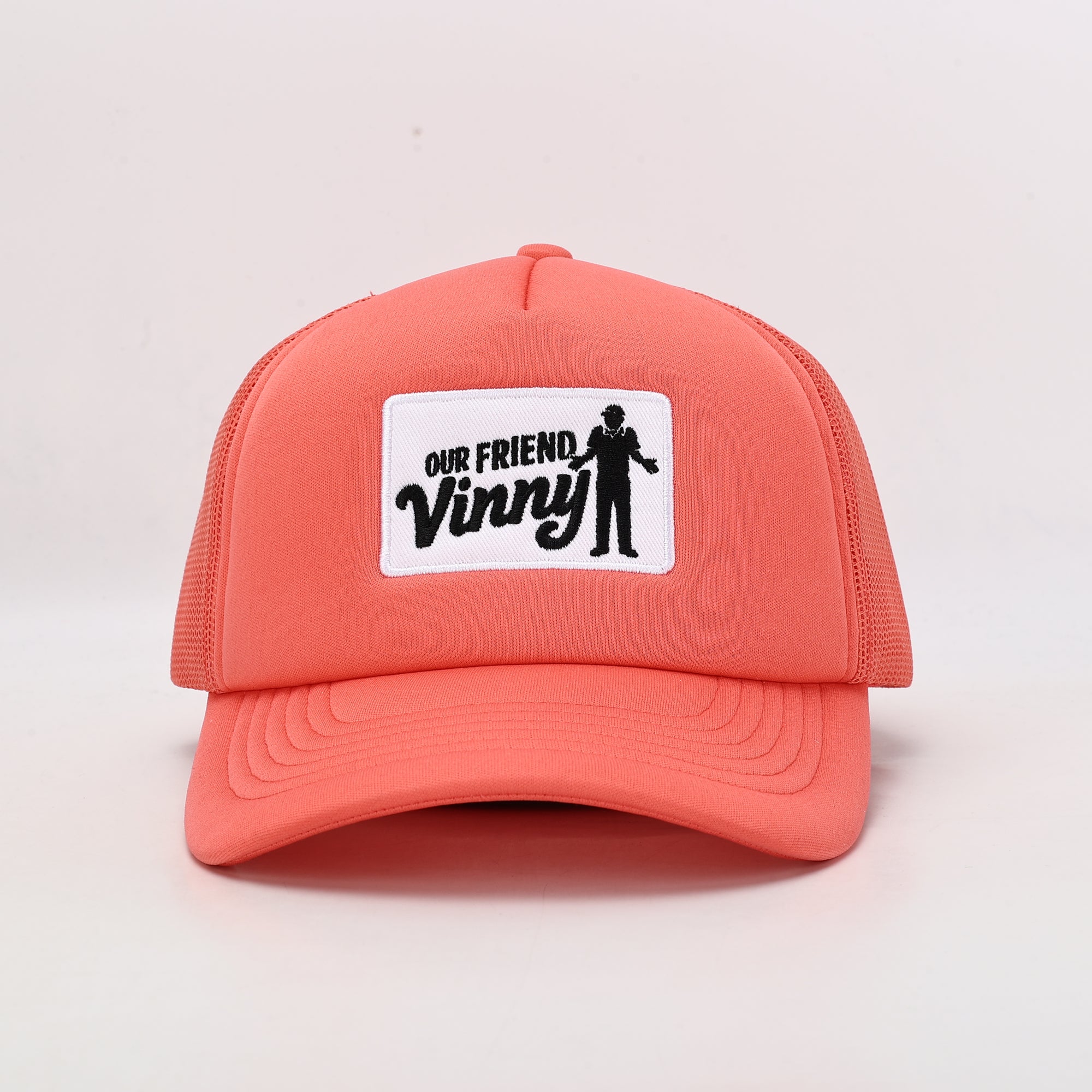 Coral cap with 'Our Friend Vinny' patch on a light gray background