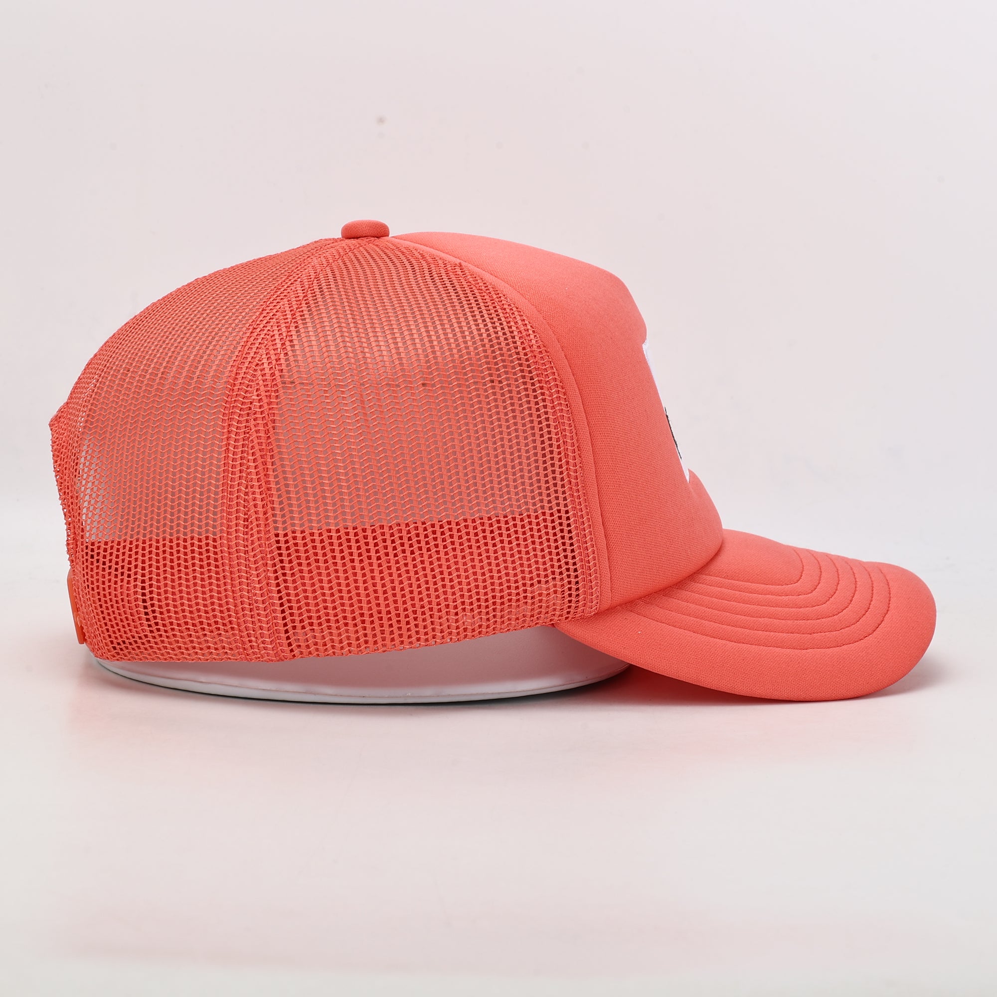 Coral pink cap with mesh back on a light gray background