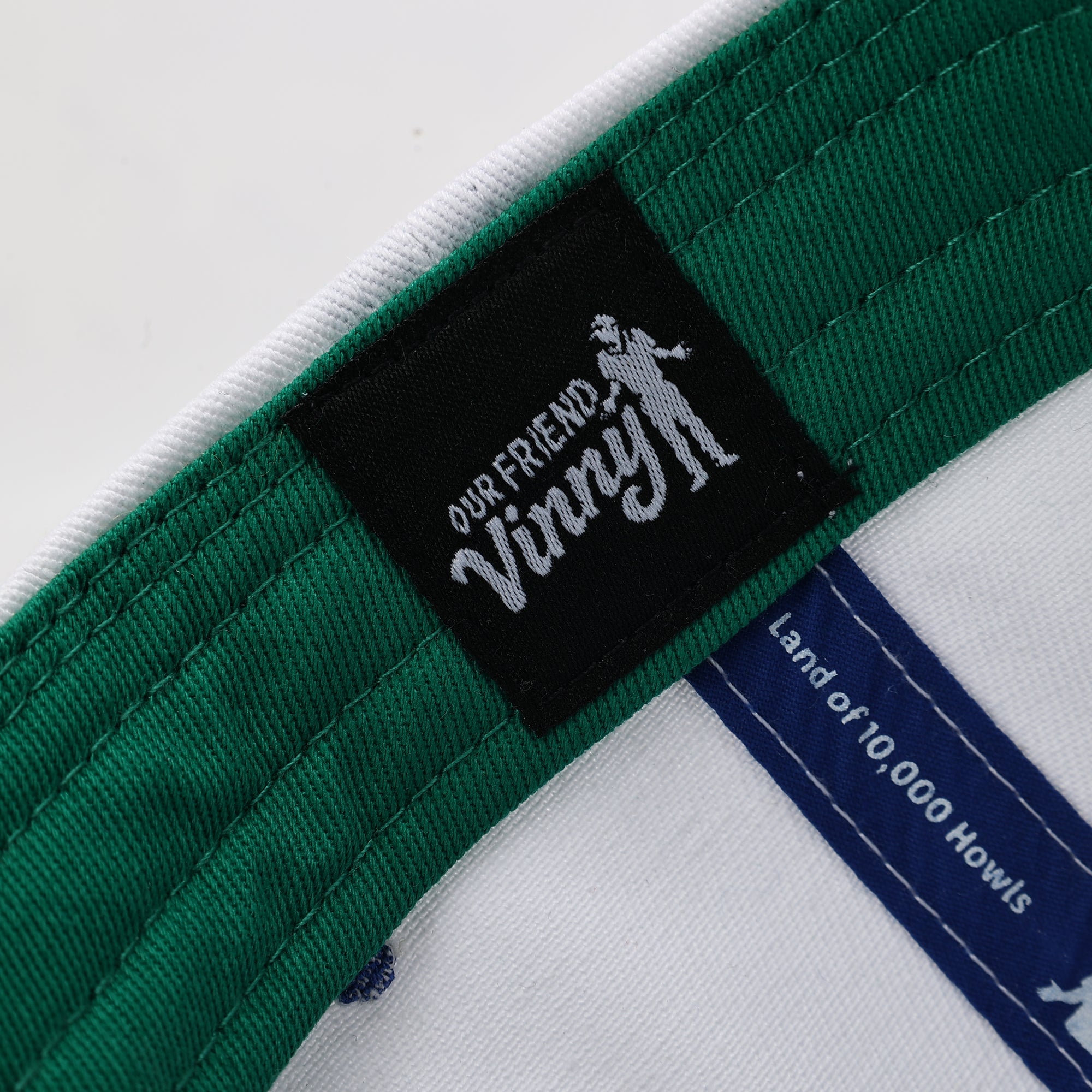 Close-up of a green belt with a black label featuring 'Our Friend Vinny' on a white background.
