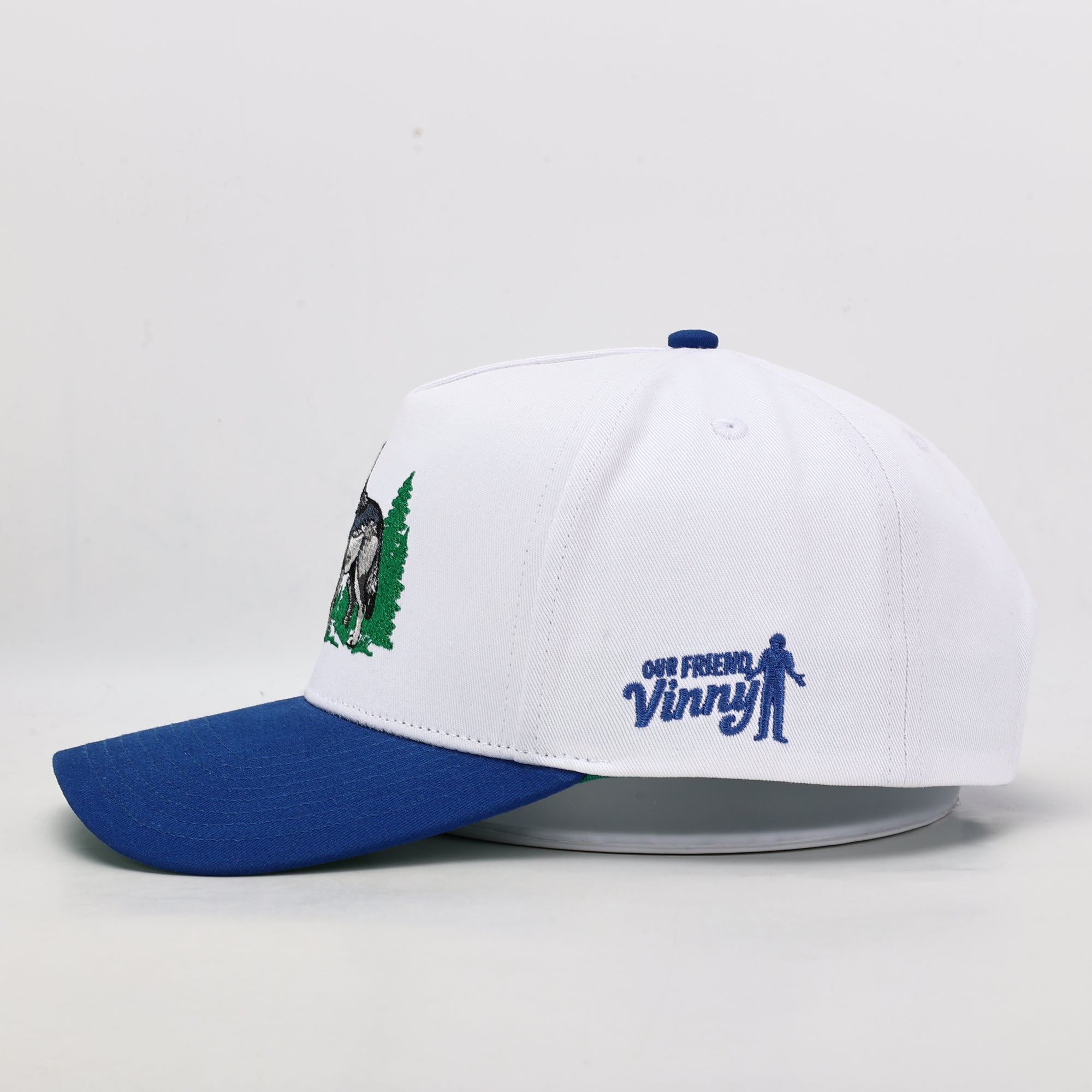 White and blue cap with embroidered designs on a light gray background