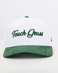 White cap with green brim and 'Touch Grass' text on a white background