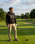 Golfer wearing the black Put Me Down for an 8 hoodie on a golf course fairway at golden hour