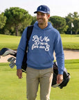 Golfer carrying his bag on the course wearing the blue Put Me Down for an 8 hoodie and a navy Our Friend Vinny cap