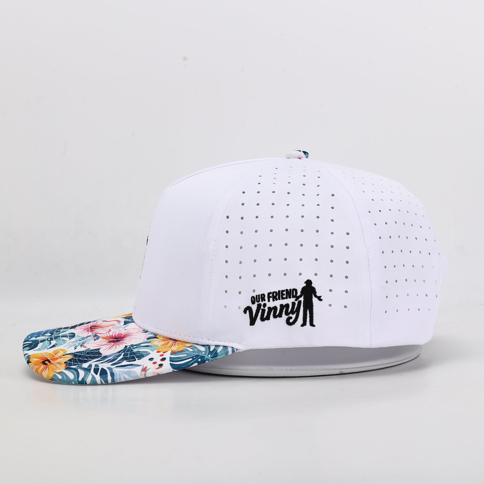 White performance cap with floral brim and 'Our Friend Vinny' logo on a light gray background
