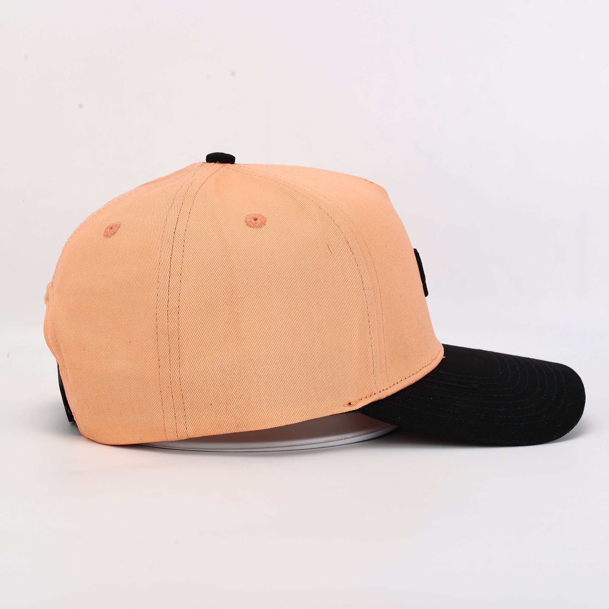 Two-tone peach and black cap on a light gray background