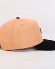 Two-tone peach and black cap on a light gray background